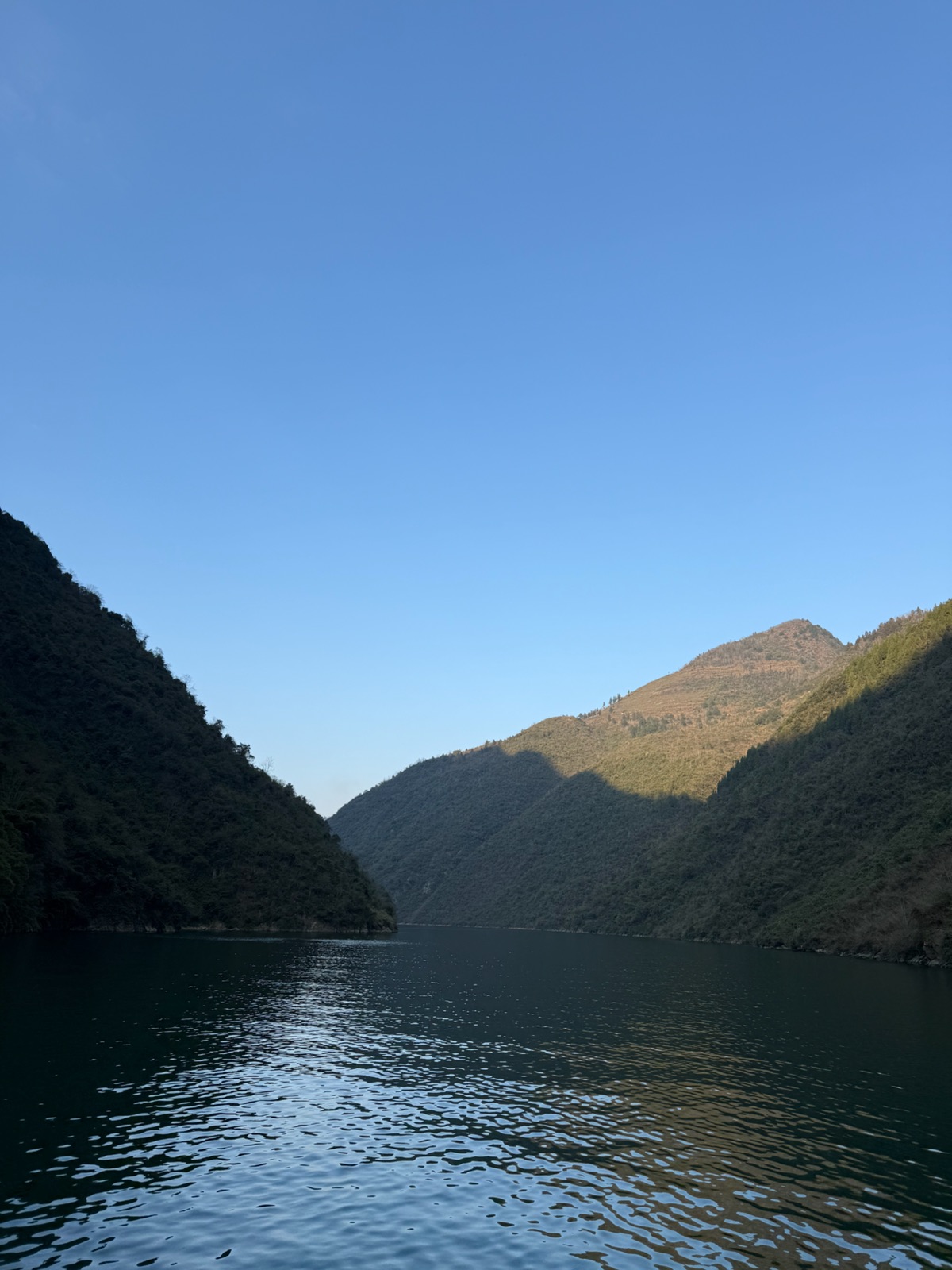 Forested cliffs and blue water seen from the Wu River boat route
